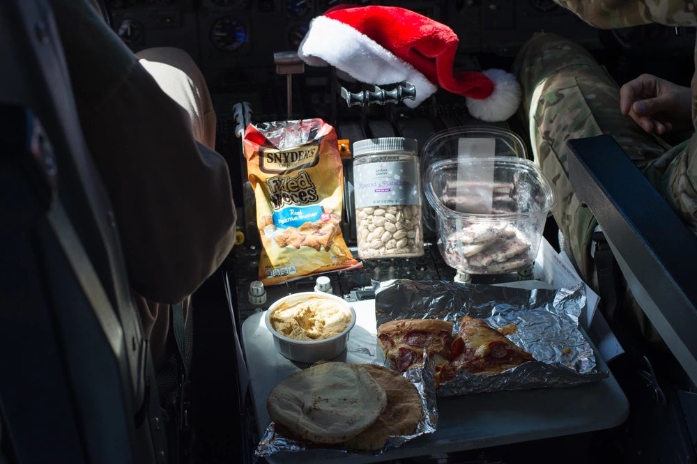 An aircrew eats a holiday meal while flying a sortie in support of Combined Joint Task Force-Operation Inherent Resolve over Iraq, Dec. 25, 2016. During the flight the crew snacked on oven-ready chicken nuggets, pizza and pita bread. (Senior Airman Tyler Woodward/U.S. Air Force)