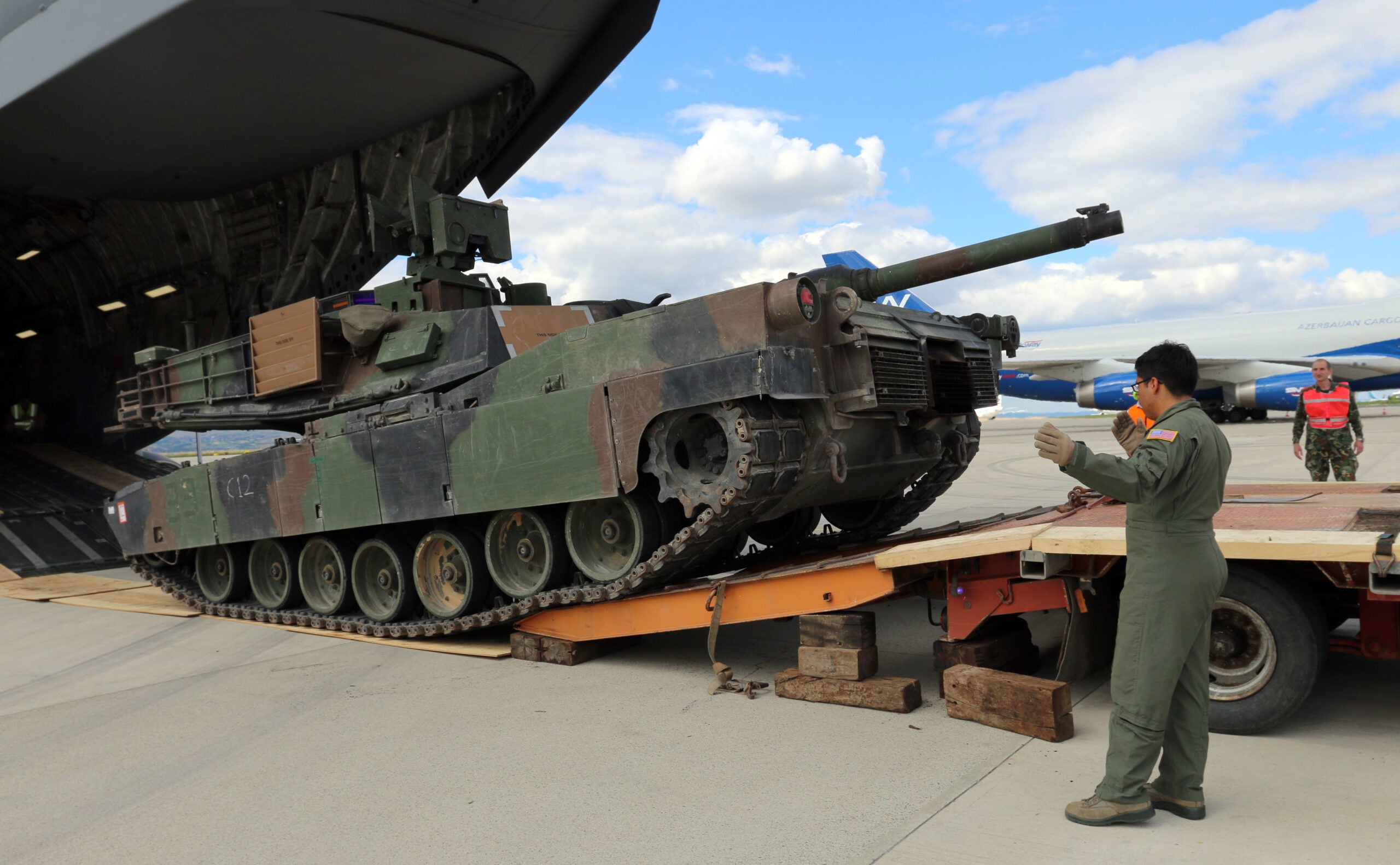 Airman 1st Class Eric E. Anaya, C-17 Loadmaster, 4th Airlift Squadron, United States Air Force, and a native of Omaha, Neb., guides an M1A2 Abrams tank onto a truck for transport after it was unloaded from a C17, Burgas, Bulgaria, June 22. Transported as part of a tank section from Germany to Bulgaria, the Abrams tank will be used by soldiers from 3rd Battalion, 69th Armor Regiment, and 2nd Squadron, 2nd Cavalry Regiment, alongside Bulgarian soldiers from the 6th Brigade Battle Group, during a tank live fire exercise during Operation Speed and Power. Operation Speed and Power is a joint training exercise which will demonstrate U.S. Army Europe's preparedness to deliver strategic effect in Atlantic Resolve-South by showcasing the freedom of movement to maneuver and fire M1A2 Abrams anywhere along the Eastern Flank. This ability enables the NATO allies to defend themselves against all threats, and shows that the alliance remains ready to defend itself anywhere at any time. (U.S. Army photos by Spc. Jacqueline Dowland, 13th Public Affairs Detachment)