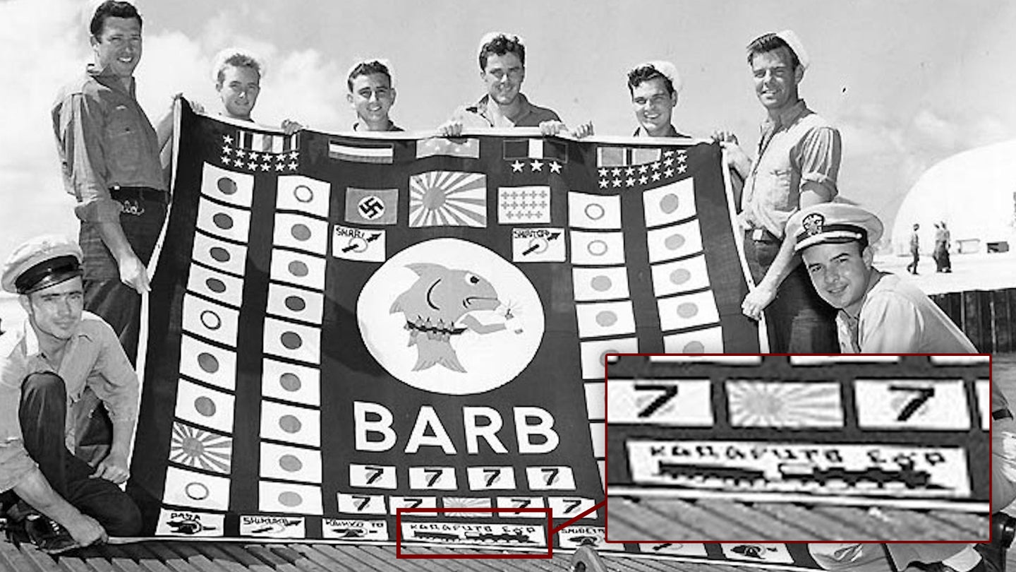 Members of the USS Barb's crew hold the submarine's battle flag aloft after returning from a final patrol in 1945.  The train kill can be seen in the bottom-center of the flag. (U.S. Navy)