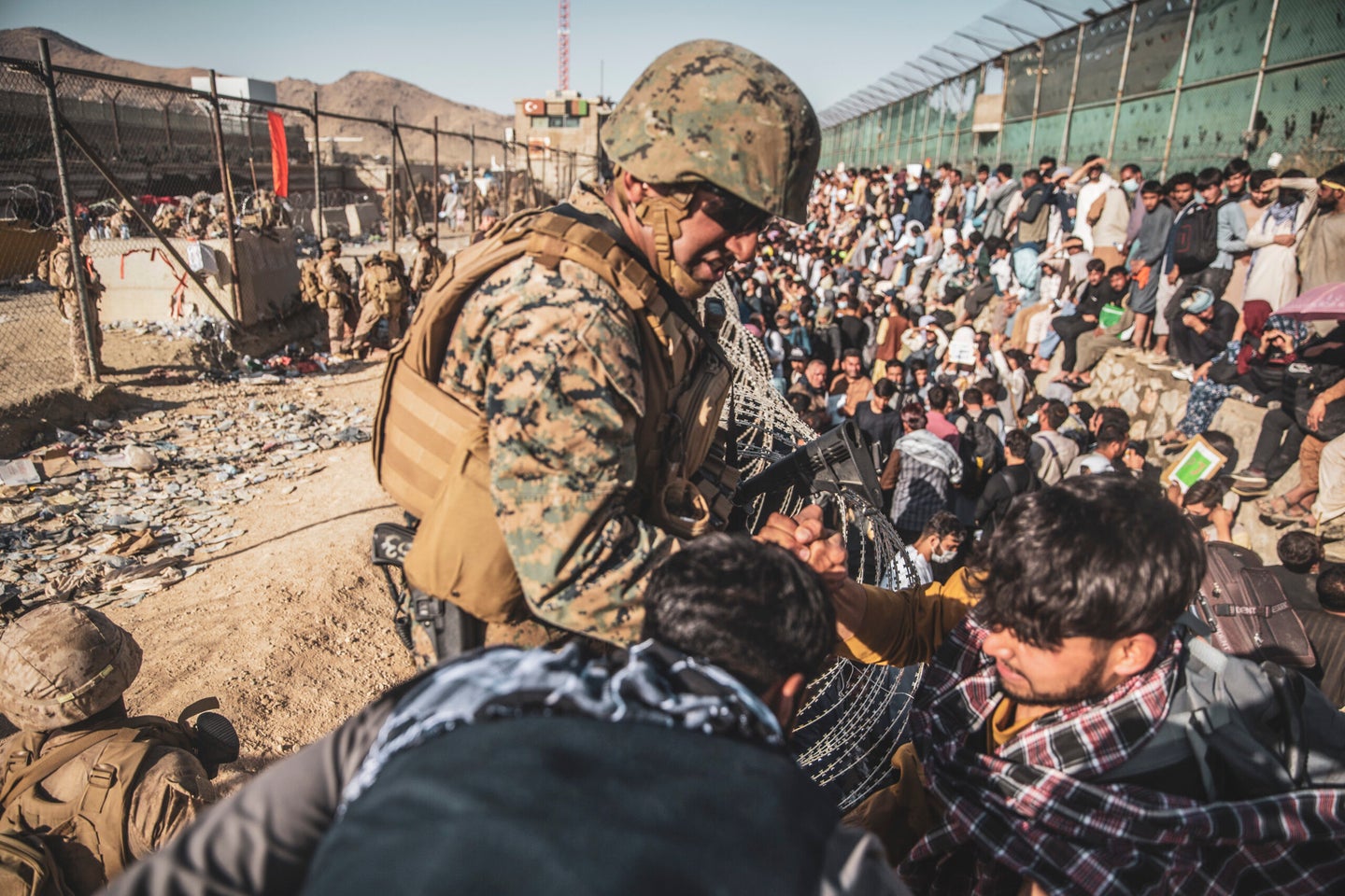 A U.S. Marine with Joint Task Force - Crisis Response assists evacuees at an Evacuation Control Check Point 
 during an evacuation at Hamid Karzai International Airport, Kabul, Afghanistan, Aug. 26, 2021. (Staff Sgt. Victor Mancilla/U.S. Marine Corps) 