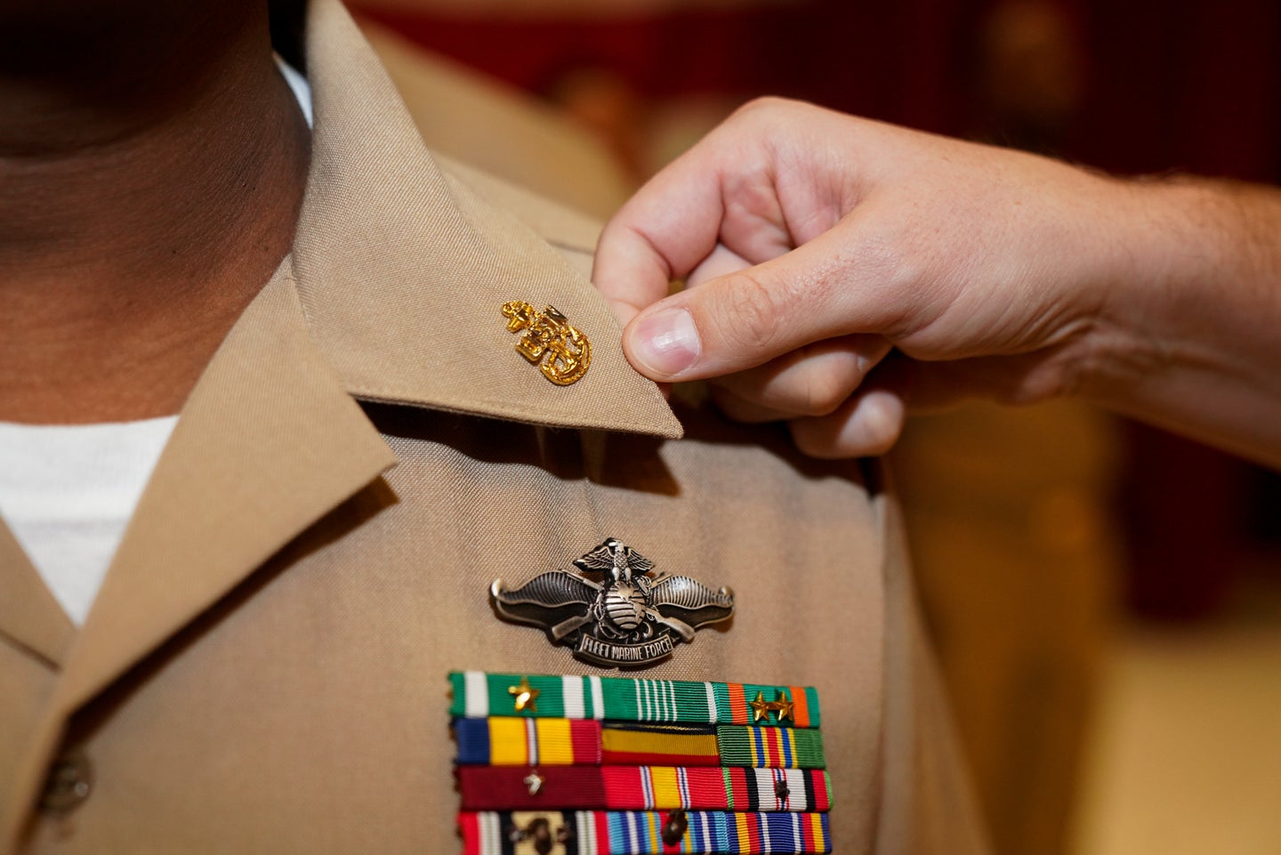 A sailor is pinned with the rank of chief petty officer by his mentor during a ceremony.
