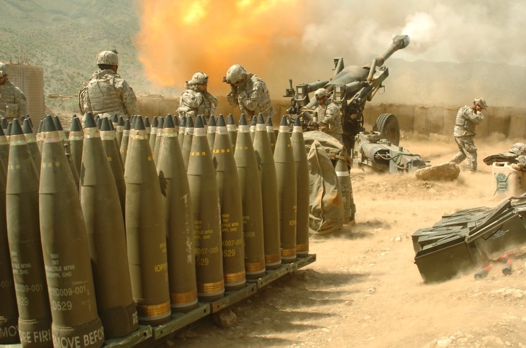 Troops shooting artillery with rounds in the foreground.