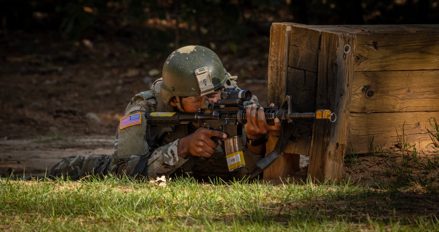 Army basic training trainee firing his M4 with a blank adapter attached.