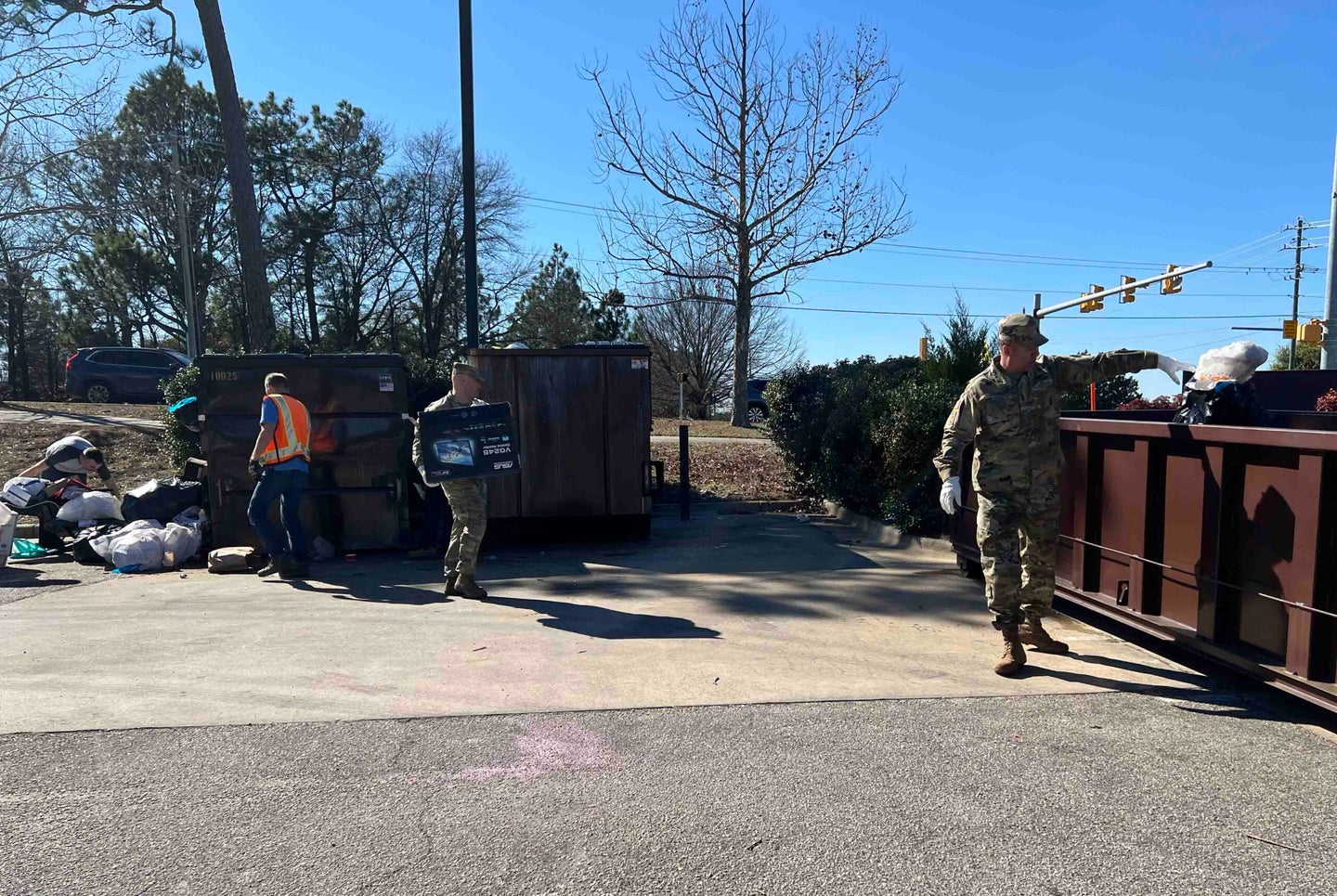 Fort Liberty Garrison Commander Col. John Wilcox, Command 
Sgt. Major Gregory Seymour, and Director of Public Works employees move trash 
to alleviate the trash overflow accumulation on the installation. (U.S. Army photo 
by Jason Ragucci, Garrison Public Affairs).