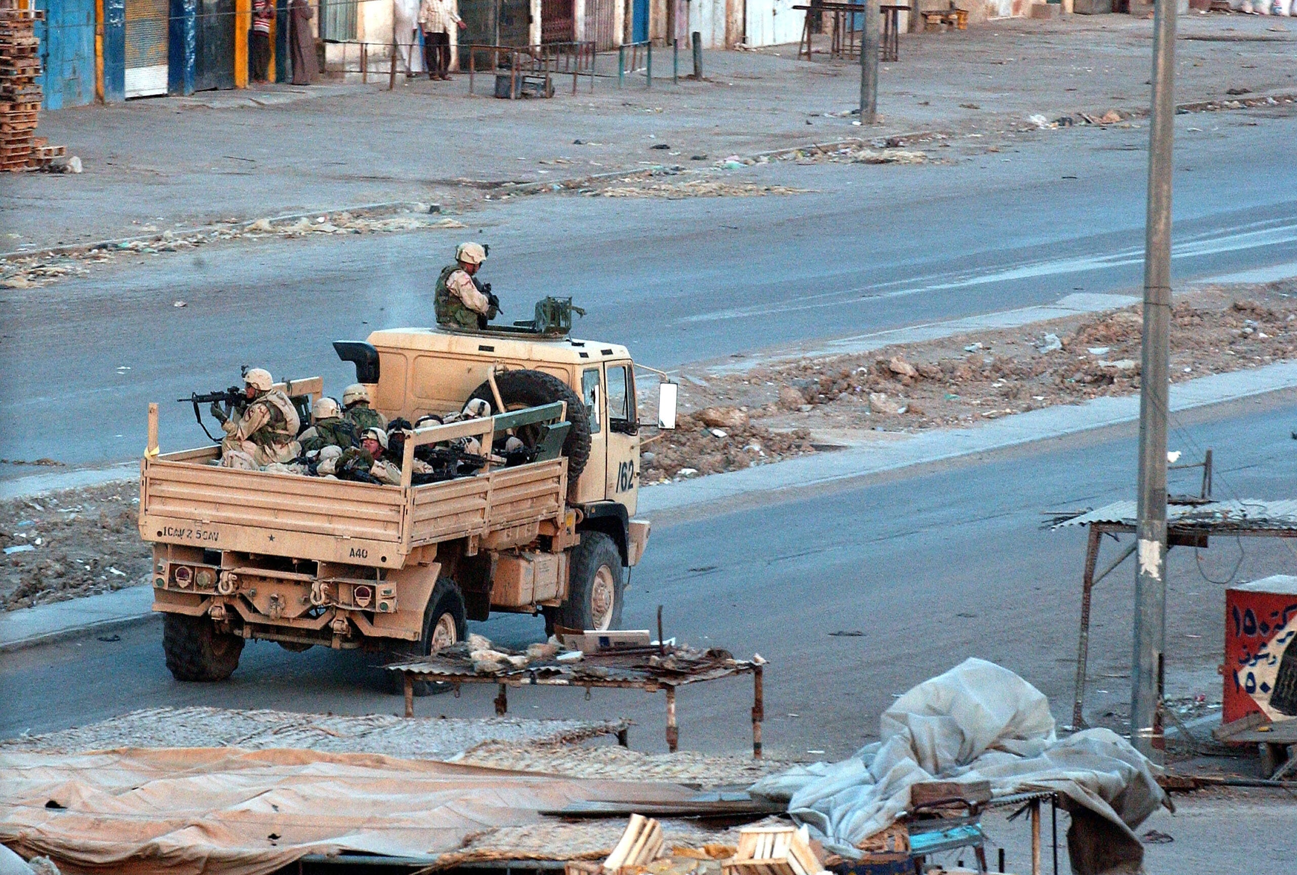SADR CITY, IRAQ - APRIL 4:  U.S. troops patrol the deserted streets of the sprawling Shia slum of Sadr City at sunset after a day of tense clashes across the country with supporters of controversial Shia cleric Moqtada al-Sadr April 4, 2004 in Sadr City, Iraq. Sadr city, a power base of the young firebrand cleric, is the home of several million poor Shi'ites and sits at the eastern edge of the capital Baghdad.  Earlier, in the southern city of Najaf, protestors and Sadr gunmen opened fire on a coalition base, sparking a thee hour gun battle that left 4 El Salvadoran soldiers and 14 Iraqis dead, and dozens more wounded.   (Photo by Wathiq Khuzaie/Getty Images)