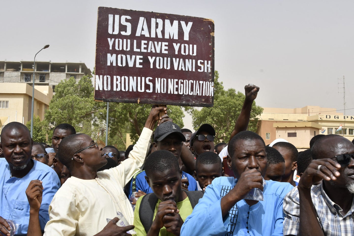 Protesters react as a man holds up a sign demanding that soldiers from the United States Army leave Niger without negotiation during a demonstration in Niamey, on April 13, 2024. Thousands of people demonstrated on April 13, 2024 in Niger's capital Niamey to demand the immediate departure of American soldiers based in northern Niger, after the military regime said it was withdrawing from a 2012 cooperation deal with Washington. (Photo by AFP) (Photo by -/AFP via Getty Images)