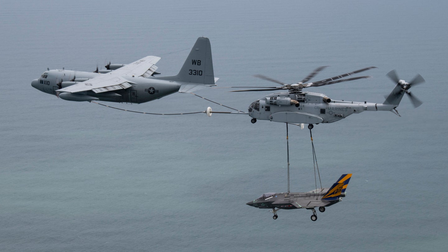 Check out this Navy tanker that’s refueling a Marine helicopter that’s carrying a Navy fighter