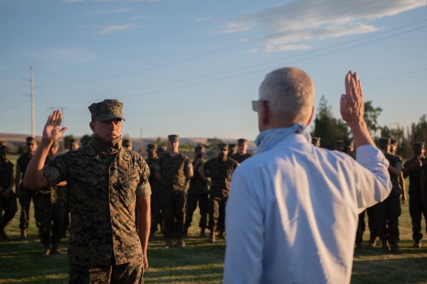 Former Defense Secretary Jim Mattis raises his knife hand to reenlist a lucky Marine corporal