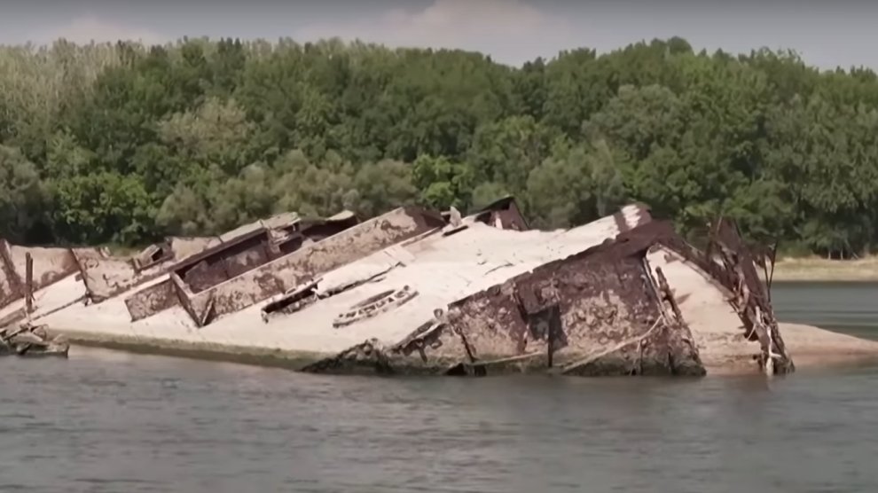 A rusted hull of a World War II Nazi warship protruding from the dried-up bed of the Danube River.