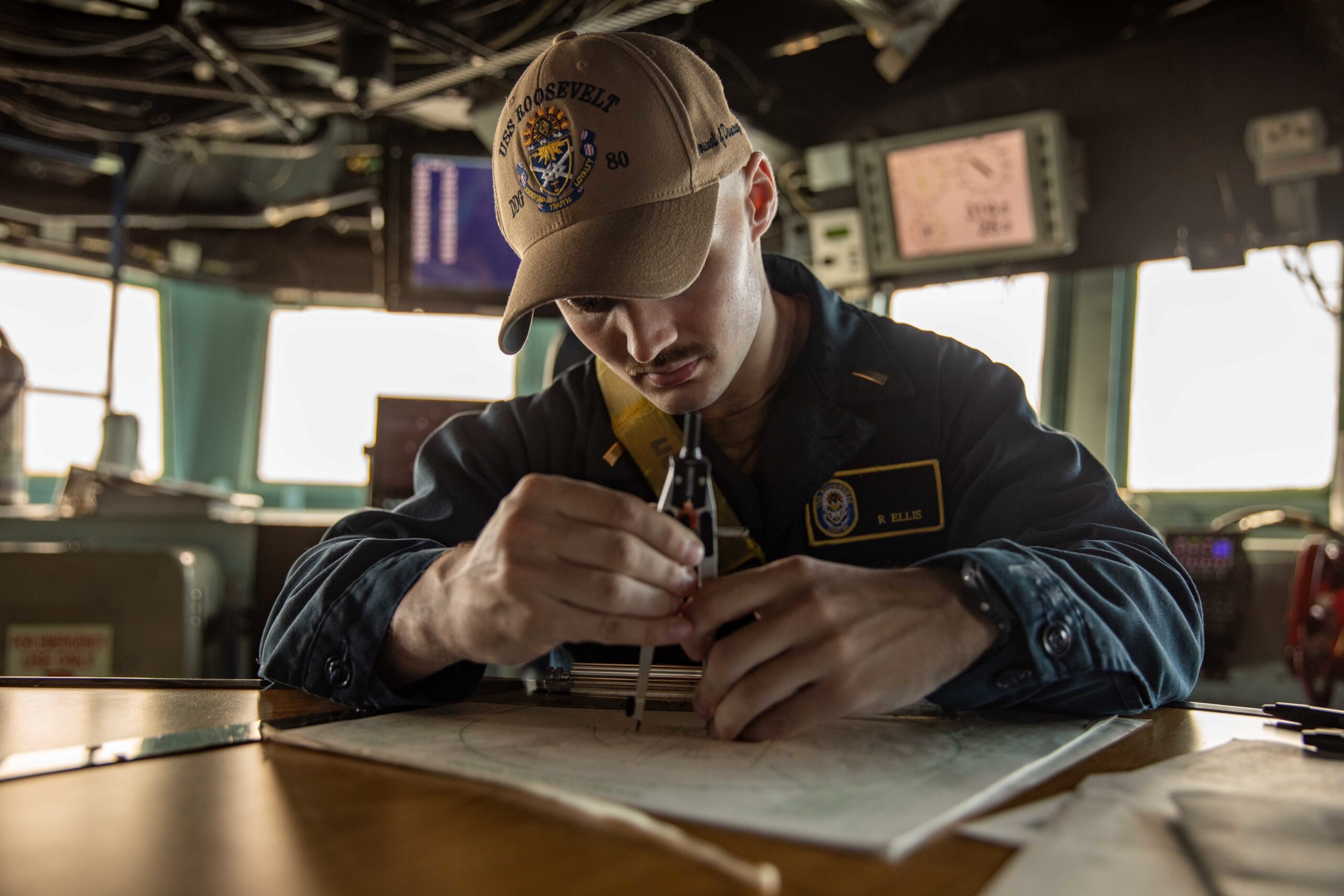 Ensign Ryan Ellis uses a protractor to map out the ship’s position in the pilothouse of the Arleigh Burke-class guided-missile destroyer USS Roosevelt on Nov. 17, 2022.