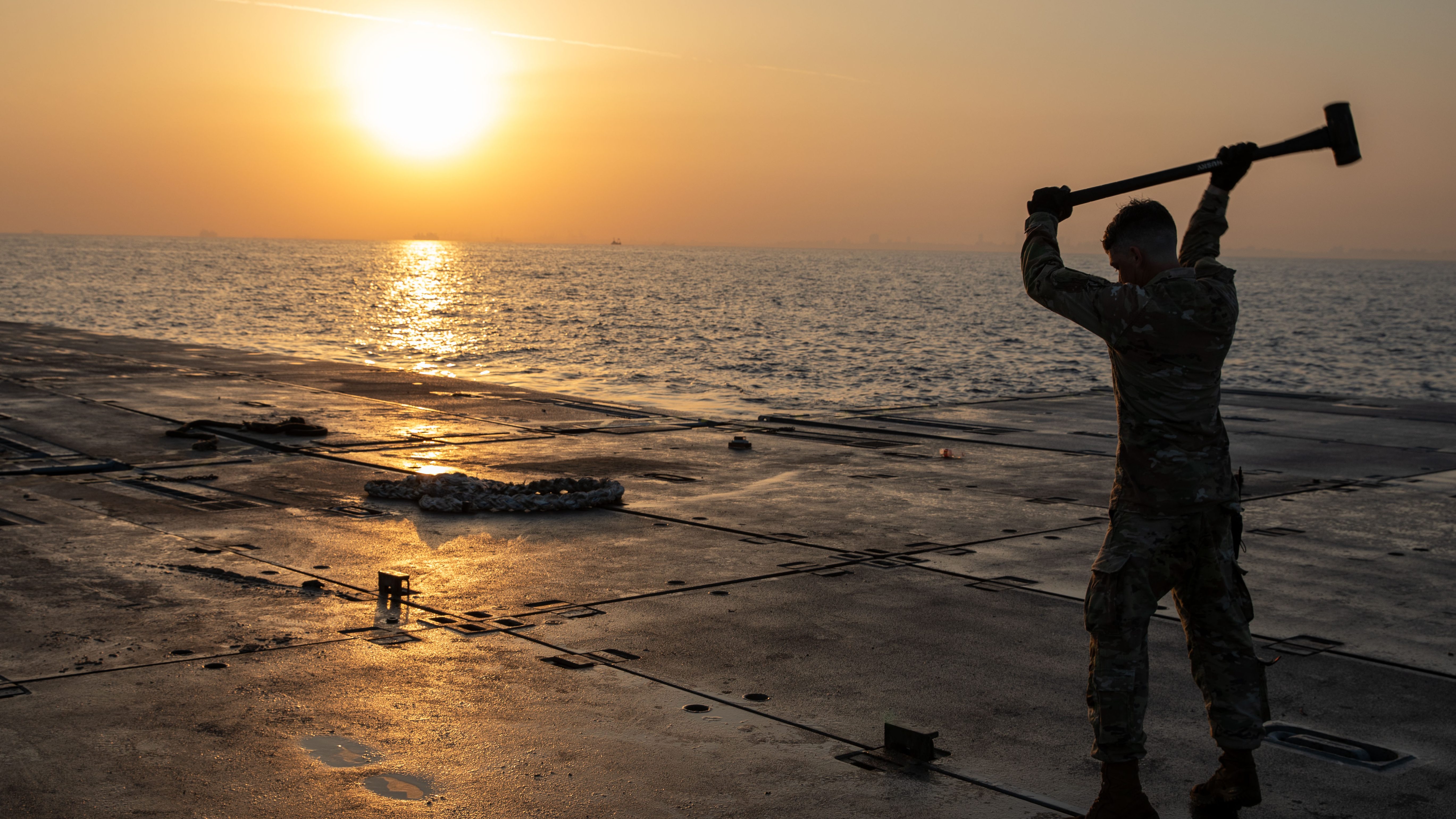 A U.S. Army Soldier assigned to the 7th Transportation Brigade (Expeditionary), repairs the Trident Pier on the Gaza coast, June 7, 2024. The temporary pier, part of the Joint Logistics Over-the-Shore capability, enables the maritime delivery of international humanitarian aid to Gaza for distribution to Palestinian people in need. (U.S. Army photo by Staff Sgt. Mikayla Fritz)
