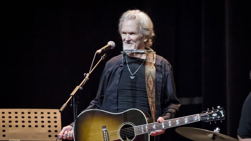 Singer Kris Kristofferson on stage in Berlin in 2019, smiling and holding his guitar.