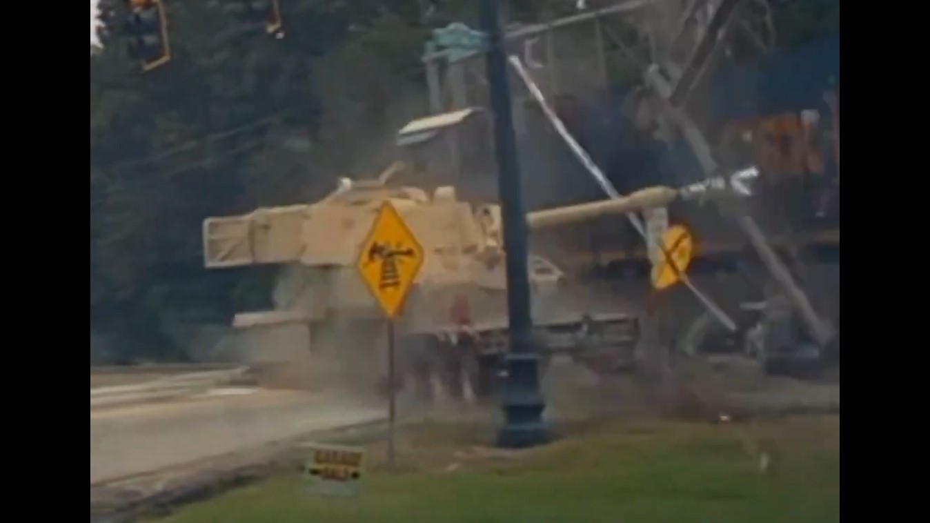 A M109 Paladin on a trailer that is stuck on railroad tracks bucks from a direct hit from a freight train.