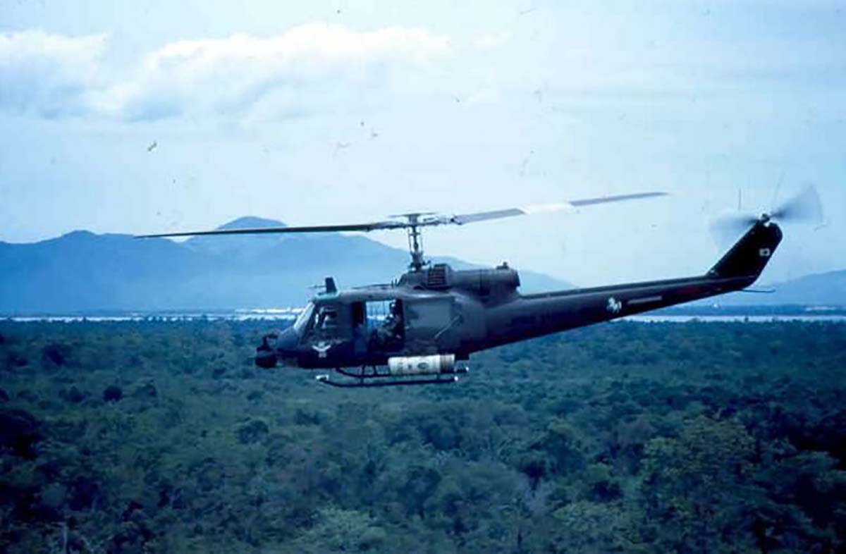 A UH-1 Huey helicopter with a Coors can painted rocket launcher on a mission during the Vietnam War.