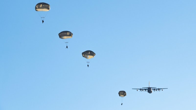 U.S. Army paratroopers with the 2nd Infantry Brigade Combat Team (Airborne), 11th Airborne Division, “Arctic Angels,” descend over Malemute Drop Zone after jumping from a U.S. Marine Corps KC-130J Super Hercules during joint airborne operations at Joint Base Elmendorf-Richardson, Alaska, Dec. 8, 2023. Marine Corps aviators from Marine Aerial Refueler Transport Squadron (VMGR) 153 out of Marine Corps Air Station Kaneohe Bay, Hawaii, and Army paratroopers conducted the joint airborne sustainment training to ensure mission readiness in an arctic environment. (U.S. Air Force photo by Airman Raina Dale)