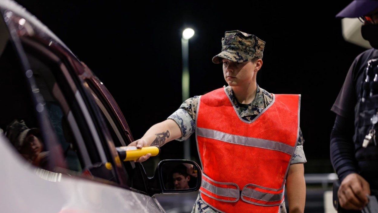 A Marine holds a breathalyzer to a driver at a security checkpoint in Okinawa.