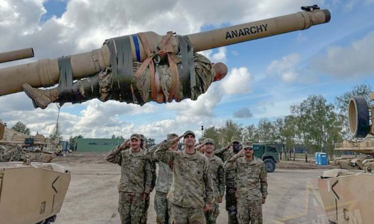 A tank platoon leader strapped to his tank's main gun.