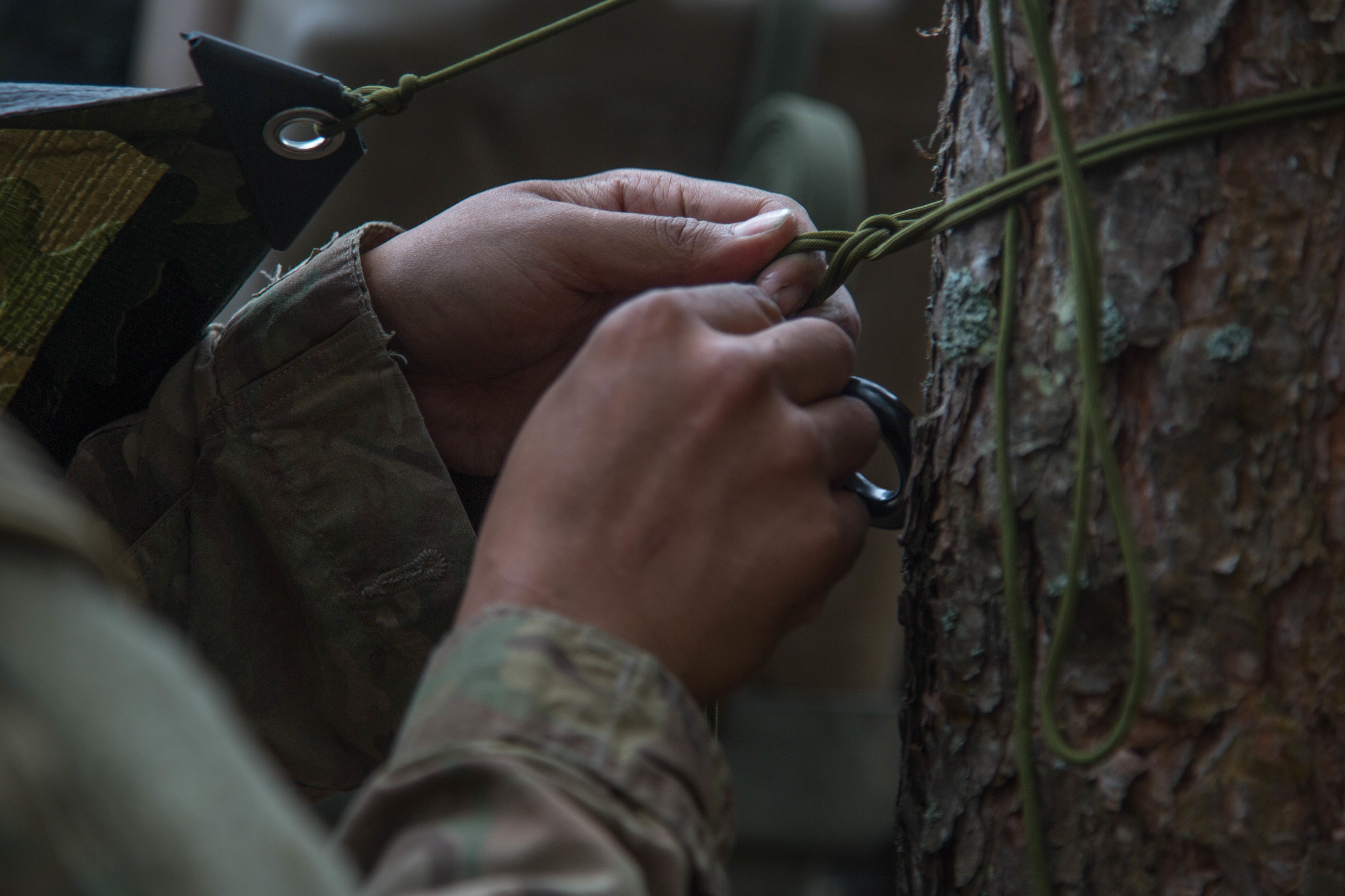 Soldiers use 550 cord to hang hammocks in the woods during a training exercise.