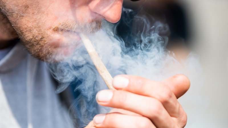 07 May 2022, Berlin: A man smokes a joint of medical cannabis at the Brandenburg Gate during the kick-off rally of a demonstration for the swift legalization of cannabis, the Global Marijuana March 2022. Photo: Christoph Soeder/dpa (Photo by Christoph Soeder/picture alliance via Getty Images)