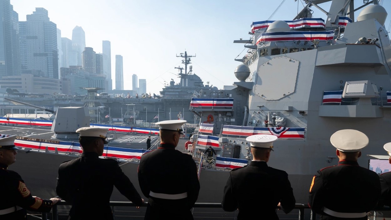 Marines look at the USS John Basilone, their backs to the camera, in full dress uniform.