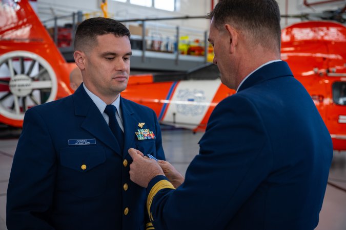 Rear Admiral. Joseph Buzzella (right) pins the Distinguished Flying Cross Medal on Lt. Cmdr. Jacob Conrad during an award ceremony at Air Station San Francisco on Dec. 12, 2024. During the ceremony, Lt. Cmdr. Jacob Conrad was awarded the Distinguished Flying Cross Medal for his actions during a search and rescue case on Dec. 30, 2023. (U.S. Coast Guard photo by Petty Officer 3rd Class Hunter Schnabel)