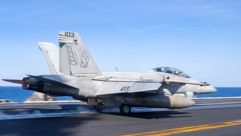 A F/A-18F moves down the runway of an aircraft carrier.