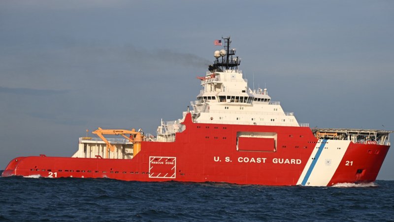 A red coast guard icebreaker sails through water.