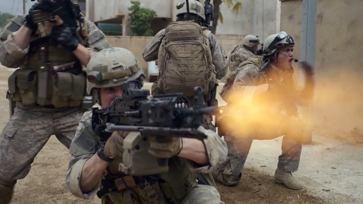 Soldiers in a street fire their weapons, the center soldier's muzzle flash filling the view.