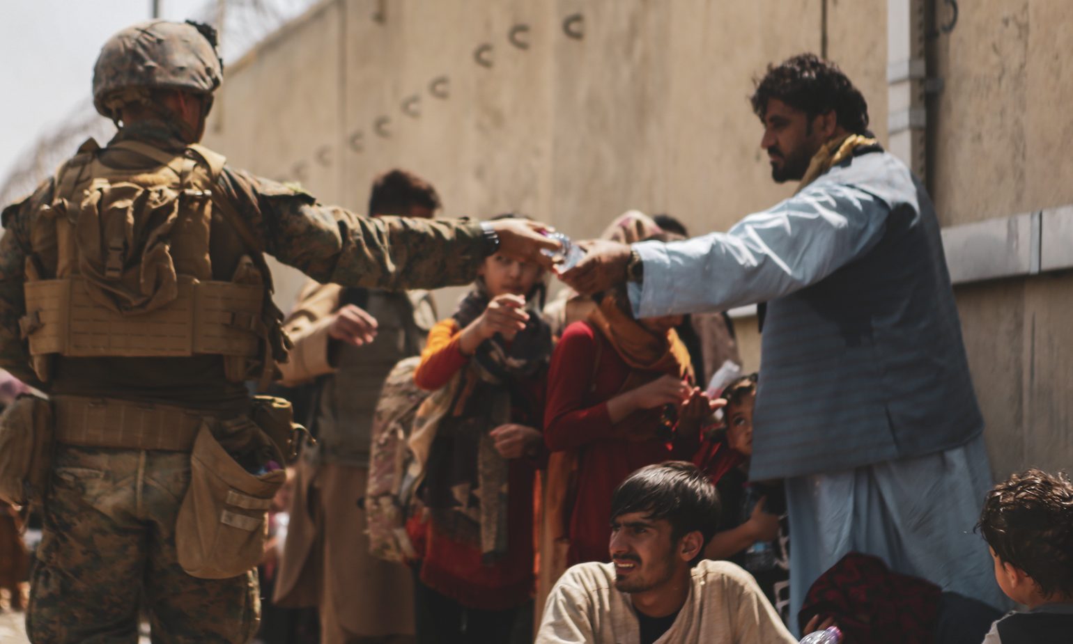 210822-M-TU241-1007 HAMID KARZAI INTERNATIONAL AIRPORT, Afghanistan (August 22, 2021) A Marine with the 24th Marine Expeditionary unit (MEU) passes out water to evacuees during an evacuation at Hamid Karzai International Airport, Kabul, Afghanistan, Aug. 22. U.S. service members are assisting the Department of State with a Non-combatant Evacuation Operation (NEO) in Afghanistan. (U.S. Marine Corps photo by Sgt. Isaiah Campbell)