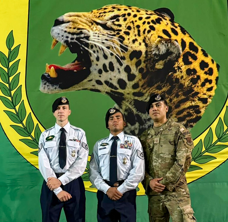 U.S. Air National Guard Staff Sgt. Grant Cozart, Tech. Sgt. Gerardo Balsa and Master Sgt. Luis Giron, defenders with the 105th Airlift Wing’s Base Defense Group, pose in front of the Brazilian Jungle Warfare School's banner after Cozart and Balsa graduated from the school in Manaus, Brazil, Nov. 22, 2024. Balsa and Cozart are two of only 50 American military members to complete the course since it was established in 1964 to develop an operational unit that could use the Amazon jungle environment to its advantage. (U.S. Air National Guard courtesy photo)