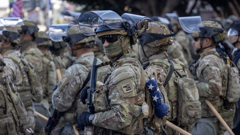 LOS ANGELES, CALIFORNIA - JUNE 12: California National Guard soldiers stand guard as protests continue in an approximately one-square mile area of downtown Los Angeles in response to a series of immigration raids on June 12, 2025 in Los Angeles, California. Protests escalated after President Donald Trump authorized military forces to protect federal property against the wishes of city and state officials who say that the Los Angeles police have the expertise and decades of experience to handle large protest crowds. National Guard troops have so far played no role in quelling violence in the streets, according to Mayor Bass, but are stationed to guard federal buildings. (Photo by David McNew/Getty Images)