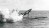 A rocket launches from the top of a submarine, spewing a huge plume of smoke, in a black and white picture.