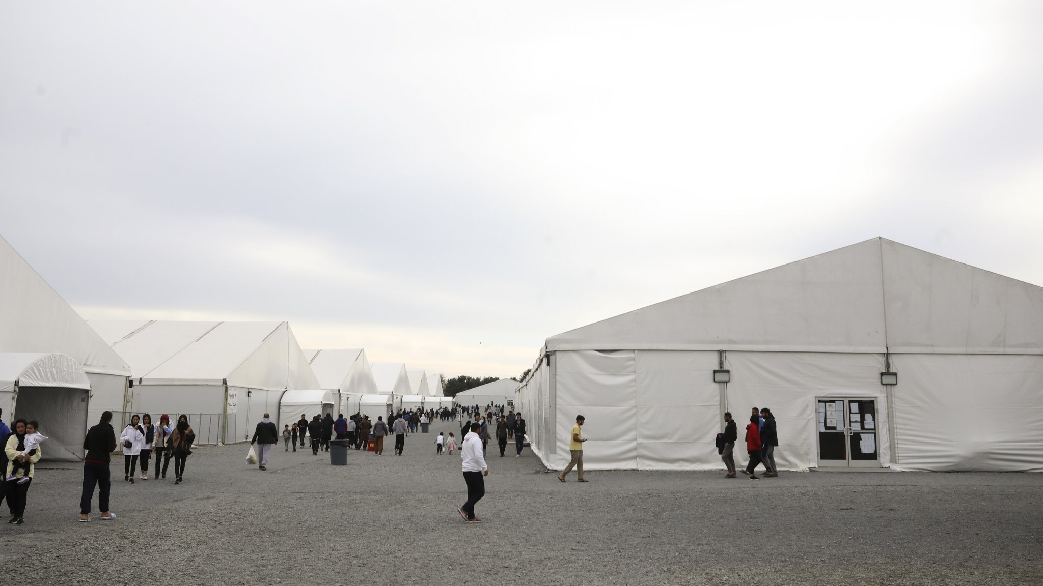 JOINT BASE MCGUIRE-DIX-LAKEHURST, NEW JERSEY - DECEMBER 02: Afghan refugees walk outside a temporary housing facility in Liberty Village on December 2, 2021 in Joint Base McGuire-Dix-Lakehurst, New Jersey. (Photo by Barbara Davidson-Pool/Getty Images)