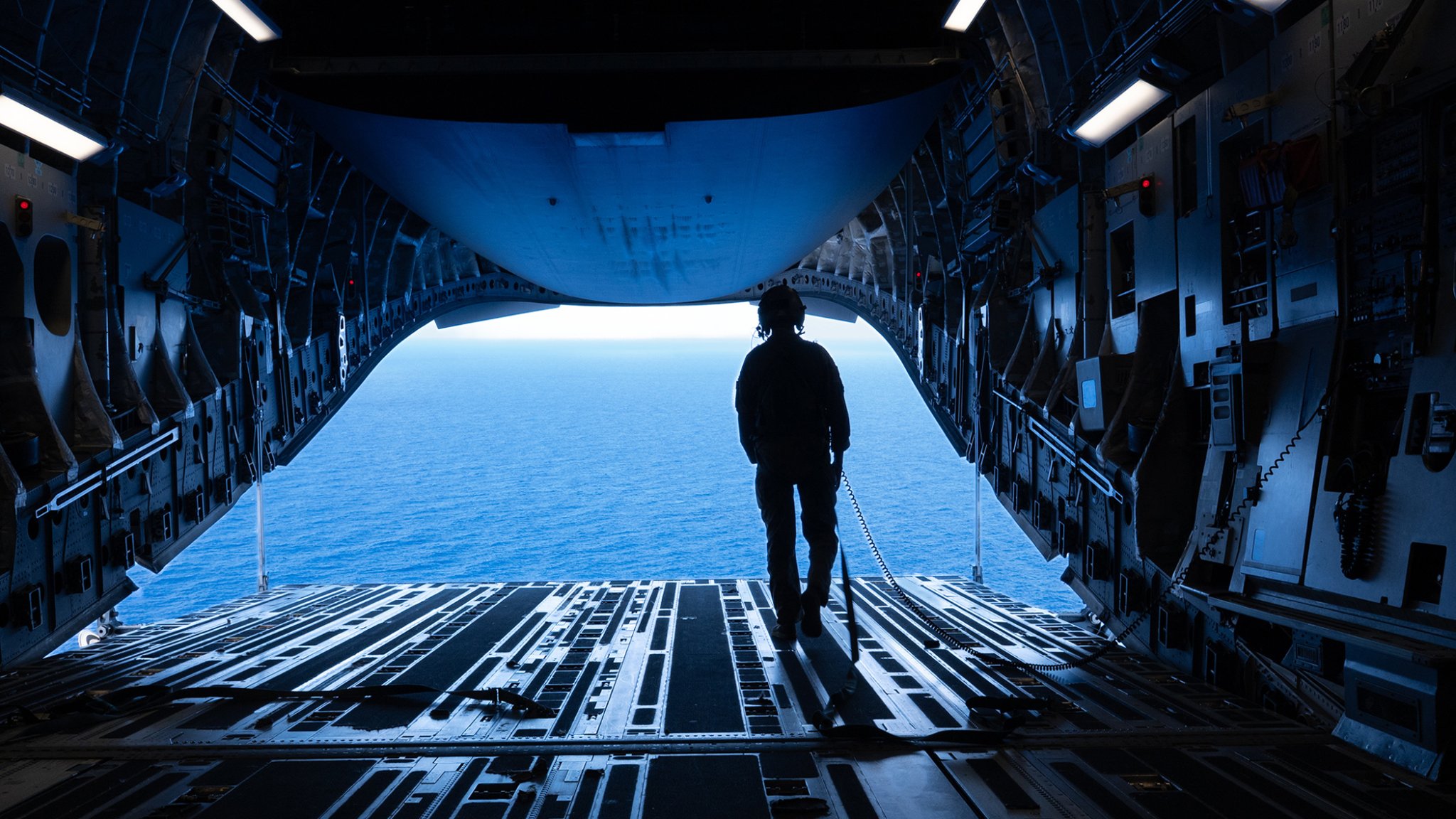 U.S. Air Force Senior Airman Dylan Weil, 16th Airlift Squadron loadmaster, looks out over the water from a C-17 Globemaster III during cargo airdrop proficiency training over the U.S. Indo-Pacific Command area of responsibility in support of Talisman Sabre 2025, July 25, 2025. Talisman Sabre is the largest bilateral military exercise between Australia and the United States, aimed at strengthening relationships and interoperability among key allies and partners to promote a safe and secure Indo-Pacific. The exercise also enhances collective capabilities to respond to a wide range of potential security concerns. (U.S. Air Force photo by Tech. Sgt. Eric Summers Jr.)