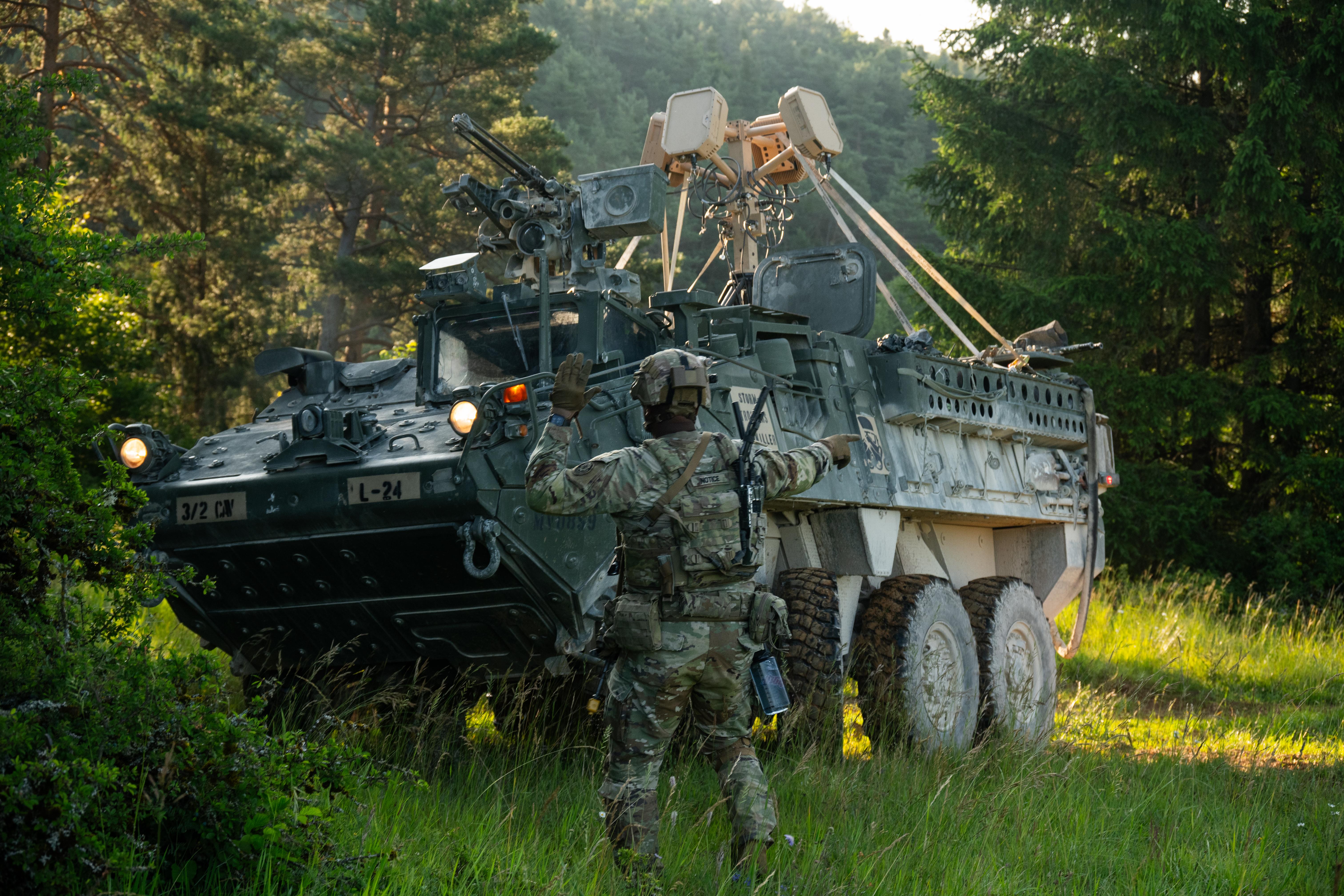 A U.S. Soldier assigned to 3rd Squadron, 2nd Cavalry Regiment guides a Stryker into concealment during Project Flytrap at Joint Multinational Readiness Center, Hohenfels Training Area, Hohenfels, Germany. The Soldiers mounted a counter-unmanned aircraft system above the Stryker, which detects frequencies of nearby drones providing ground-force Soldiers with real-time location data on their end-user devices. (U.S. Army photo by Spc. Elijah Magaña/Released)