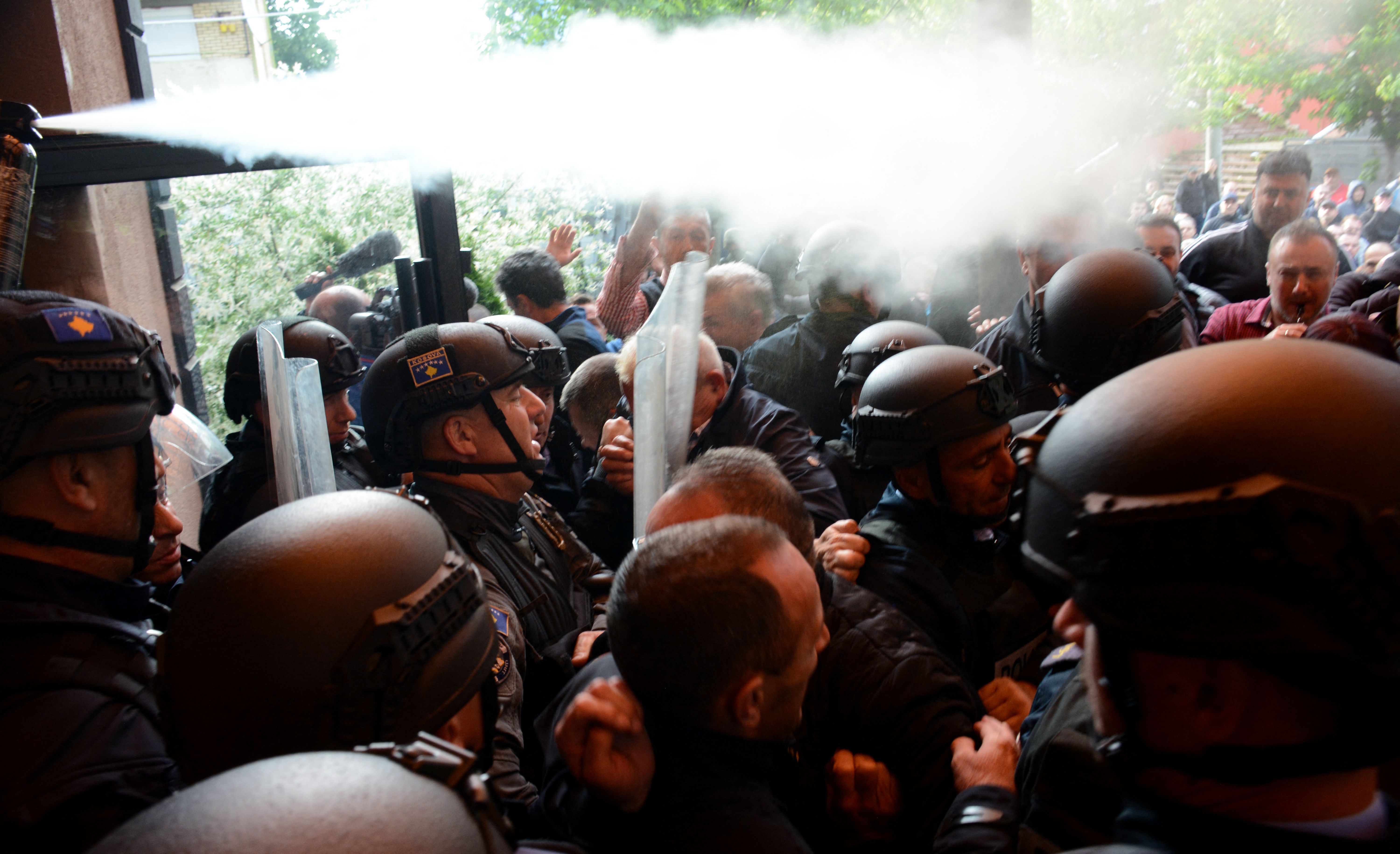 Kosovo riot police along with KFOR (International Military Mission to Kosovo) military police, secure access to a municipal building in Zvecan as Kosovo Serbs gather outside the building after police helped install ethnic Albanian mayors following controversial elections, on May 29, 2023. Police fired teargas during clashes with ethnic Serbs protesting to demand the withdrawal of law enforcement officers from northern Kosovo along with new ethnic Albanian mayors. Kosovo's ethnic Serb minority boycotted last month's elections in the north, allowing ethnic Albanians to take control of the local councils despite a tiny turnout of under 3.5 percent. (Photo by AFP) (Photo by -/AFP via Getty Images)