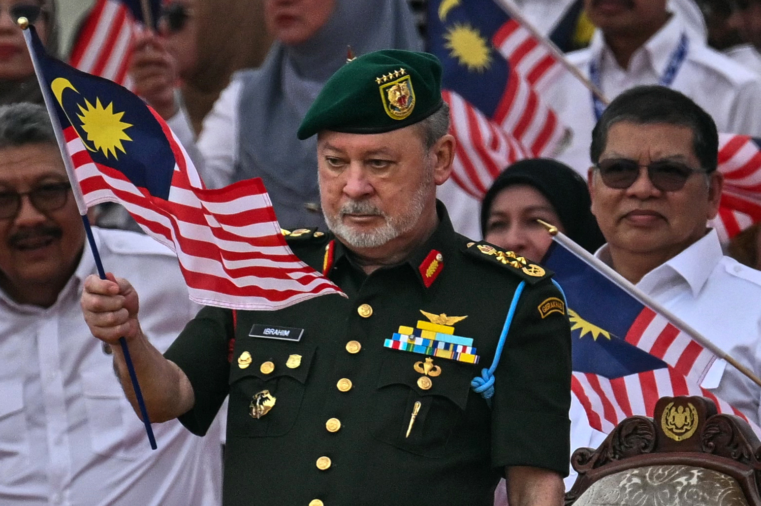 King of Malaysia Sultan Ibrahim (L) and Queen Raja Zarith Sofiah (R) wave flags during the 67th National Day celebrations in Malaysia's administrative capital Putrajaya on August 31, 2024. The country is commemorating the anniversary of independence of the Federation of Malaya from British rule in 1957. (Photo by Mohd RASFAN / AFP)