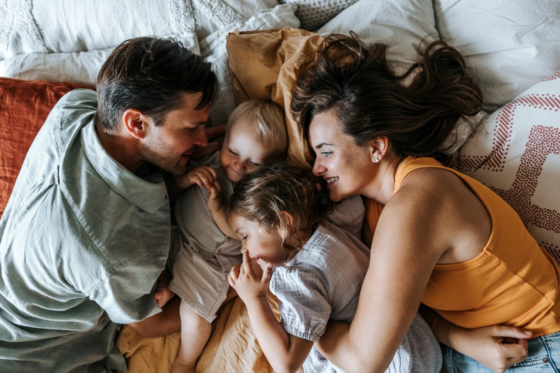 Directly above shot of parents lying down on bed with son and daughter at home