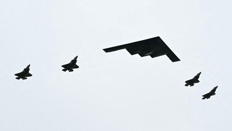 A B-2 bomber (C) and four F-35 fighter jets fly overhead as US President Donald Trump greets Russian President Vladimir Putin on the tarmac after they arrived at Joint Base Elmendorf-Richardson in Anchorage, Alaska, on August 15, 2025. Putin is in Alaska at the invitation of Trump in his first visit to a Western country since he ordered the 2022 invasion of Ukraine that has killed tens of thousands of people. (Photo by ANDREW CABALLERO-REYNOLDS / AFP) (Photo by ANDREW CABALLERO-REYNOLDS/AFP via Getty Images)