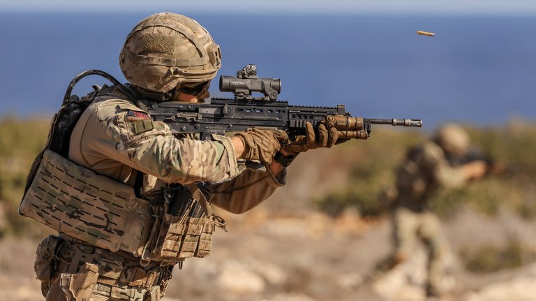 A British soldier aims a rifle.
