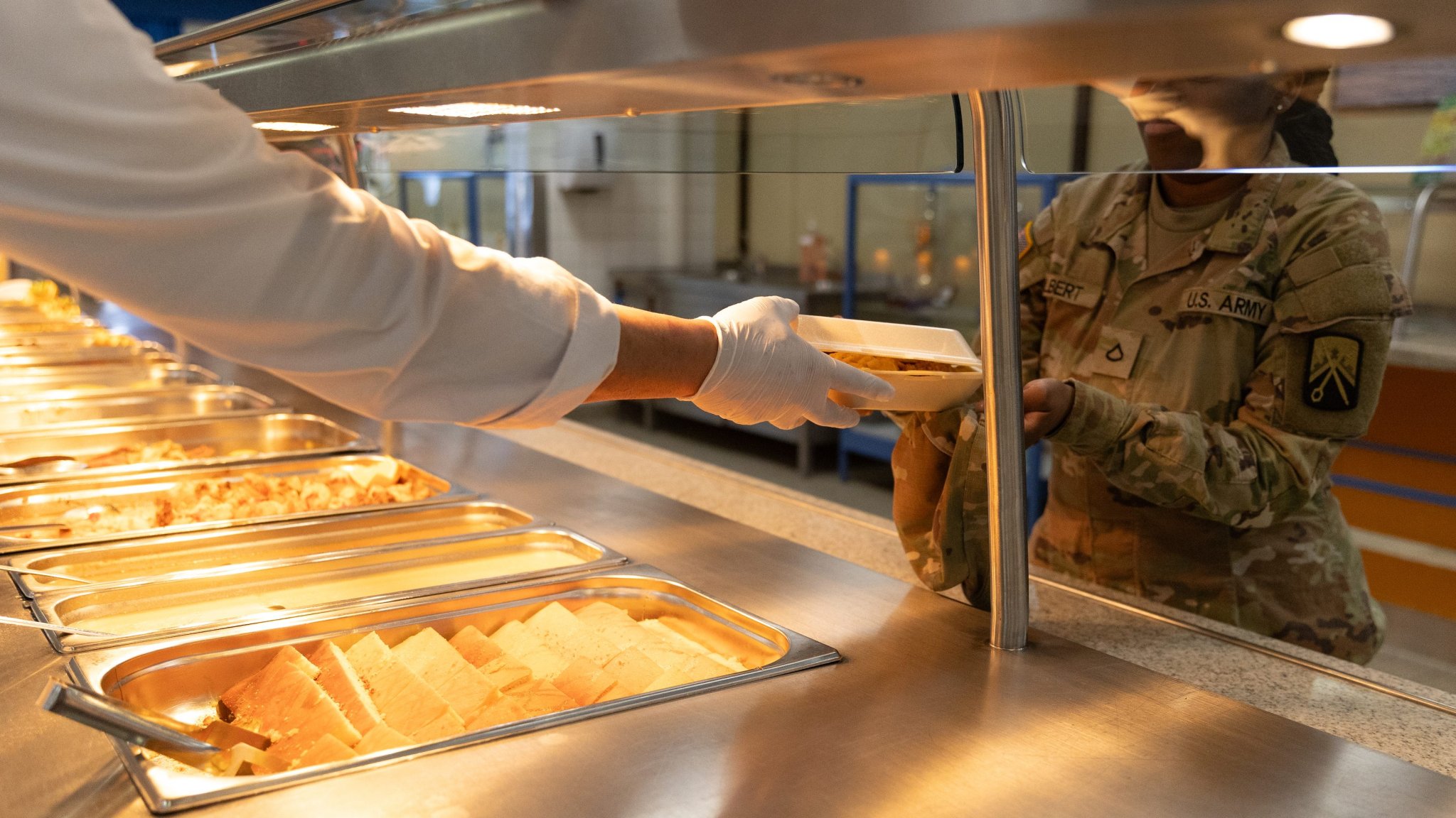 A Kleber Kaserne Clocktower Cafe Dining Facility employee hands a Soldier her lunch on March 20, 2025 at their “Welcome Back” lunch, featuring filet mignon, shrimp scampi, and king crab legs. On March 10th, the dining facility reopened its doors after a three-month closure, giving Soldiers and civilians working in the Kaiserslautern military community a healthy and reliable meal option again. (Photo by Sarah Ridenour, 21st TSC public affairs)