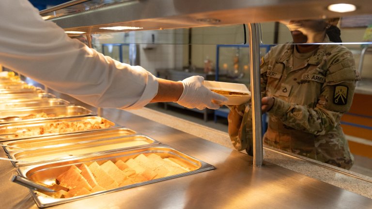 A Kleber Kaserne Clocktower Cafe Dining Facility employee hands a Soldier her lunch on March 20, 2025 at their “Welcome Back” lunch, featuring filet mignon, shrimp scampi, and king crab legs. On March 10th, the dining facility reopened its doors after a three-month closure, giving Soldiers and civilians working in the Kaiserslautern military community a healthy and reliable meal option again. (Photo by Sarah Ridenour, 21st TSC public affairs)
