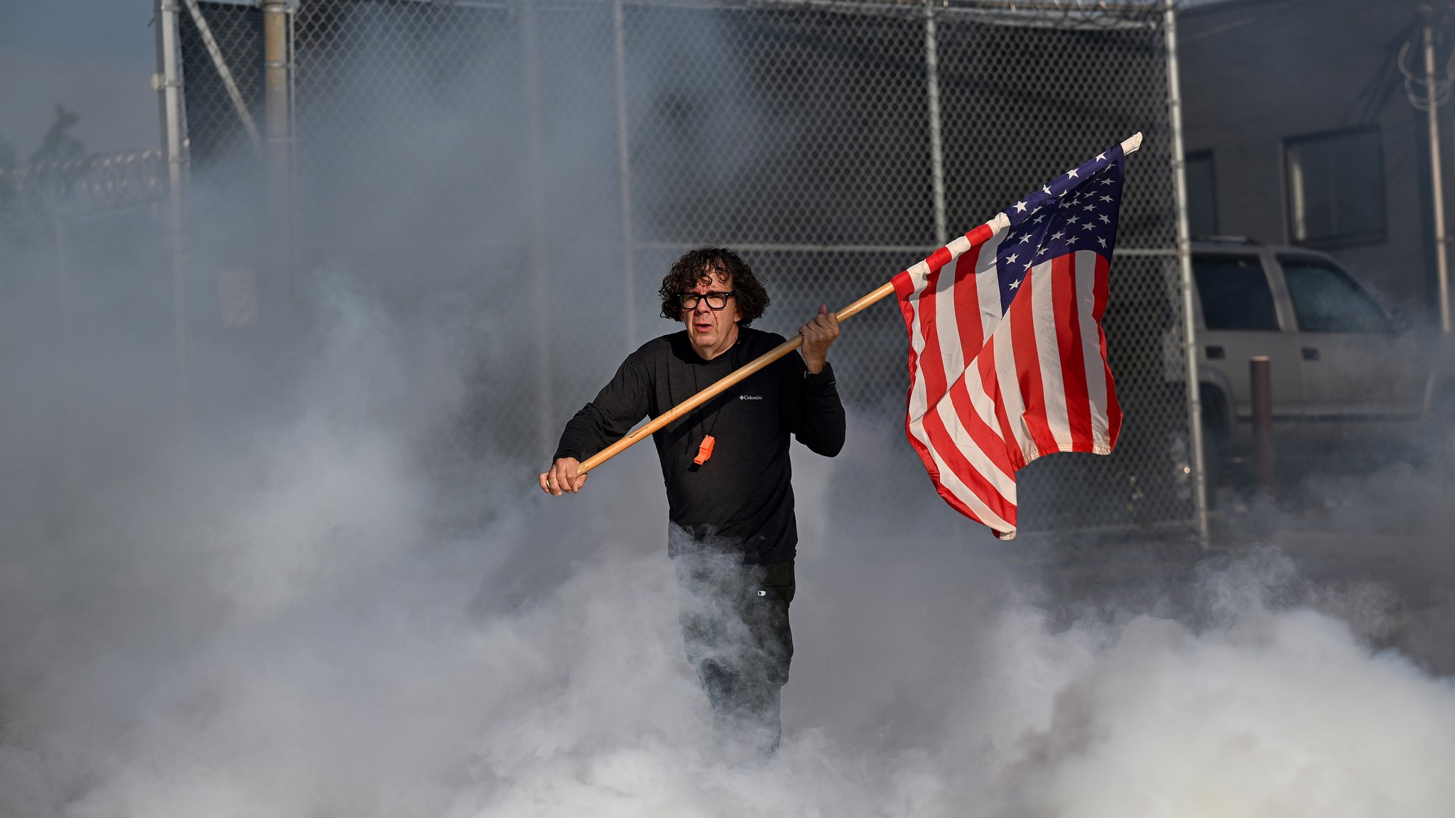 BROADVIEW, ILLINOIS - SEPTEMBER 19: Curtis Evans walks through tear gas with an American flag during a protest outside the U.S Immigration & Customs Enforcement facility on September 19, 2025 in Broadview, Illinois. Protesters were speaking out against recent ICE raids and arrest taking place in Chicago and surrounding suburbs. President Donald Trump has deployed ICE Agents and other federal agencies to Chicago to enforce immigration laws. Trump is also threatening to send the National Guard to fight crime in the city. (Photo by Joshua Lott/The Washington Post via Getty Images).