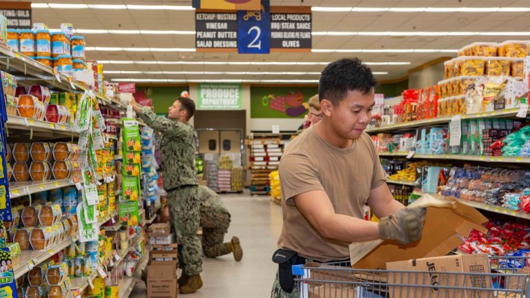 Among trounior enlisted service members with families are among those l231119-N-ML137-1033 NAVAL BASE GUAM, Guam (Nov. 19, 2023) Hull Technician 3rd Class Steven Tamse, right, and other Sailors assigned to the submarine-tender USS Frank Cable (AS 40), fill store shelves at Orote Point Commissary following a shipment of groceries, Nov. 19, 2023. The shipment is one of several high-priority grocery flights that will resupply Defense Commissary Agency (DeCA) shelves at Andersen Air Force Base (AAFB) and U.S. Naval Base Guam (NBG) before Thanksgiving. Following the discovery of an isolated insect incident at base commissaries in Guam, Joint Region Marianas engaged DeCA leadership for immediate response. The shipments of groceries will provide much needed products to military service members and their families. (U.S. Navy photo by Mass Communication Specialist 1st Class Samantha Jetzer)