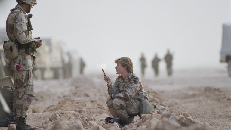 Soldiers in military fatigues in the desert, with figures visible in the background, in the Saudi–Iraqi neutral zone on the border between Saudi Arabia and the Iraq, 1991. (Photo by David Turnley/Corbis/VCG via Getty Images)