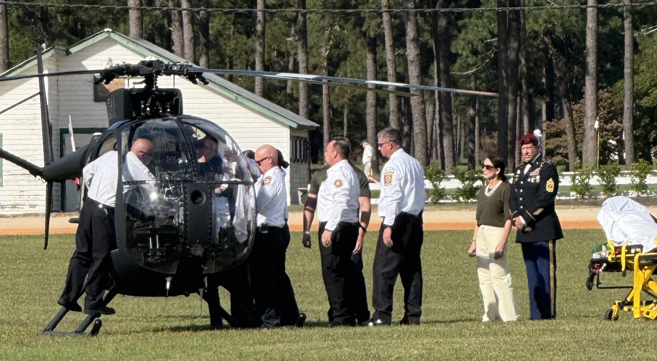 82nd Airborne pilot Garrett Illerbrunn is helped into the cockpit of a helicopter for his final flight during a retirement celebration as his wife, Lorna Illerbrunn, looks on.