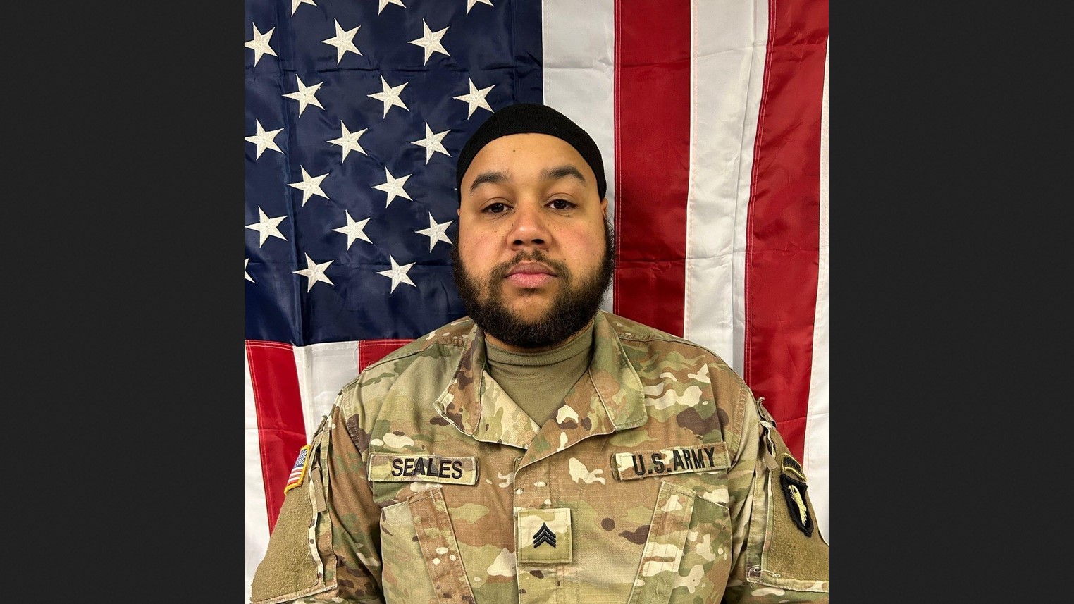 Sgt. Terell Seales stands in uniform in front of the American flag.