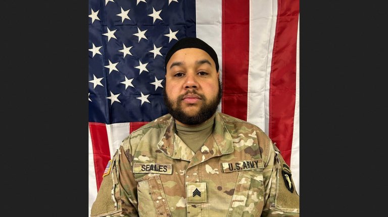 Sgt. Terell Seales stands in uniform in front of the American flag.