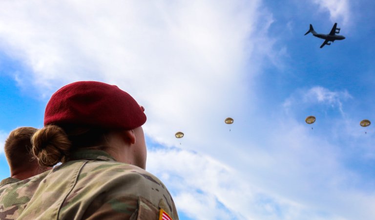 U.S. Army Capt. Meckenzie MacIlvennie, commander of the 5th Quartermaster Theater Aerial Delivery Company, 16th Special Troops Battalion, 16th Sustainment Brigade, watches as paratroopers exit an aircraft over the historic drop zone at Ginkelse Heide in Ede, Netherlands, during the 81st commemoration of Operation Market Garden, Sept. 20, 2025. The airborne operation is part of Exercise Falcon Leap, a multinational training event honoring the legacy of allied paratroopers. (U.S. Army photo by 1st Lt. Nahjier Williams)