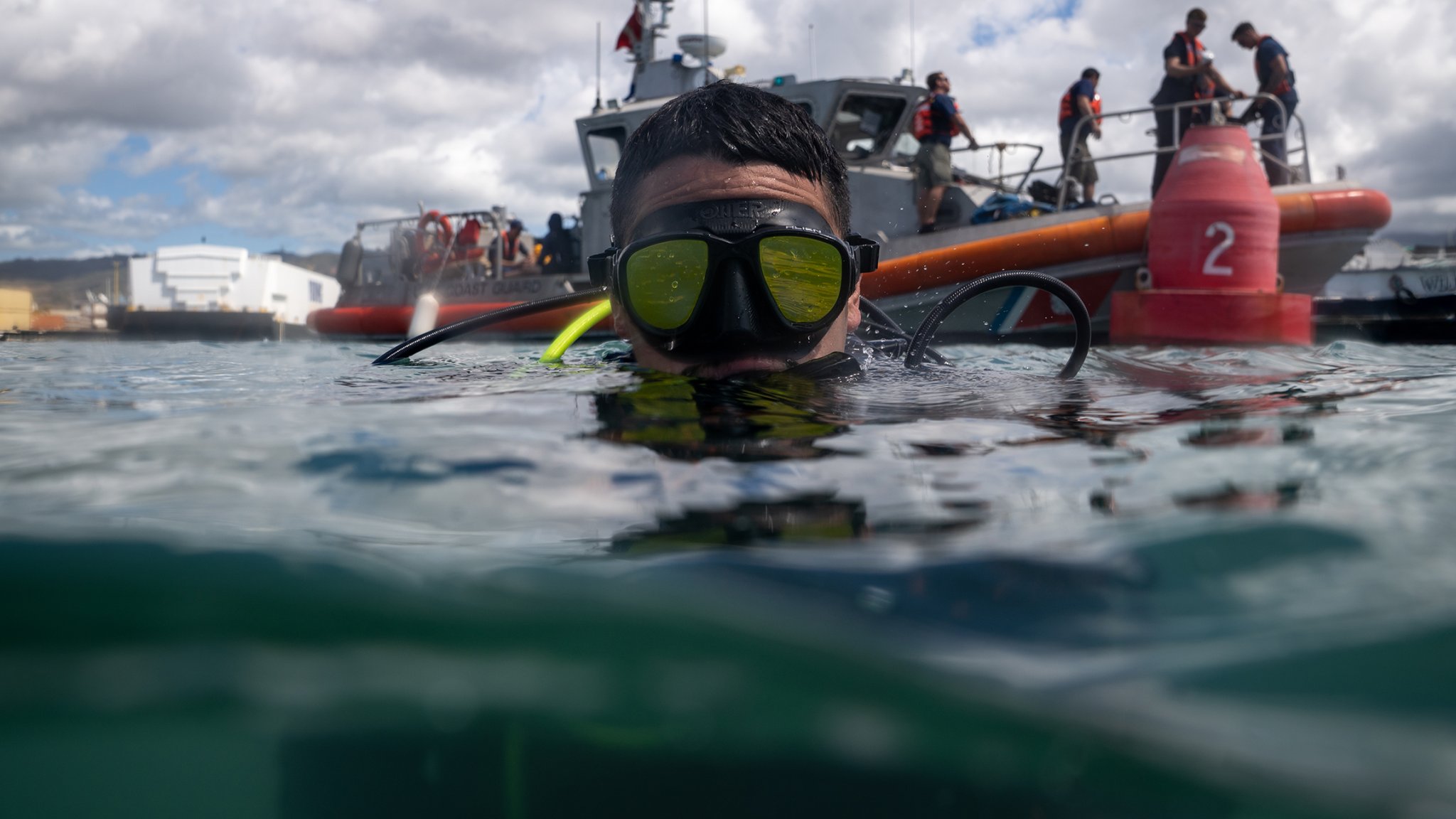 U.S. Coast Guard Petty Officer 2nd Class Nick Coronado, a diver assigned to Coast Guard Regional Dive Locker Pacific in Honolulu, Hawaii, prepares to descend below the surface in the Honolulu Harbor, Hawaii Sep. 26, 2025. Coast Guard Regional Dive Locker Pacific members and a Coast Guard Station Honolulu 45-foot Response Boat-Medium crew worked together to inspect and service channel marker buoys in Honolulu harbor, Hawaii. (U.S. Coast Guard photo by Petty Officer 2nd Class Tyler Robertson)